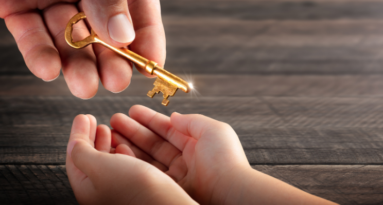 Adult handing a golden key to a child with open hands